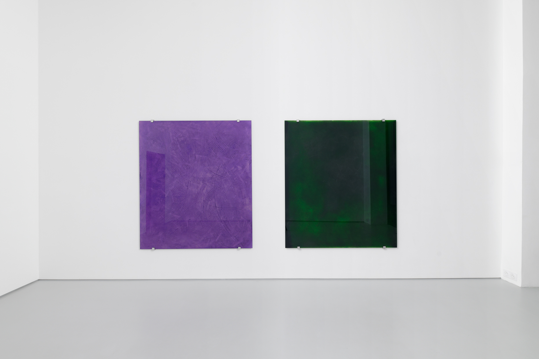 two glass paintings on a white gallery wall. The left is purple the right is dark green.